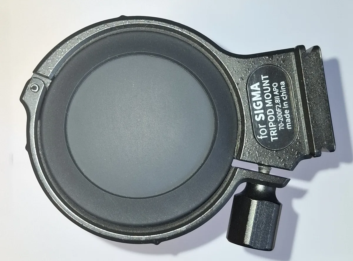 A 71 mm photography tripod ring closed around a 70 mm silicone bottle sleeve, showing how lightly it is tightened, with the Sigma part label legible